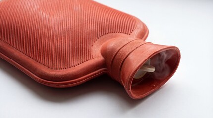 Close-up of a hot water bottle with steam coming out, placed on a white surface for warmth and comfort