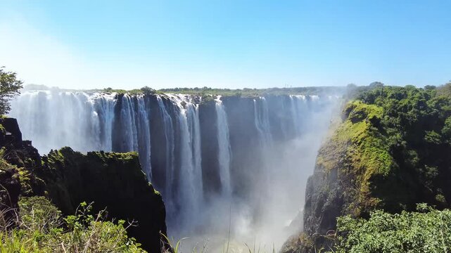 Static shot of Victoria Falls with the Zambezi River plunging over the Main Falls into the narrow gorge, mist rising above rainforest-covered cliffs near the town of Victoria Falls, Zimbabwe, Africa