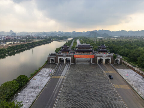 Aerial view of a grand gateway standing proudly on a broad avenue, reflecting the sky, with mountains looming in the distance, Hoa Lu, Ninh Binh, Vietnam.