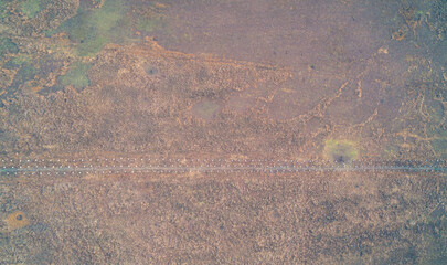 Top down aerial view of concrete dragon's teeth anti tank defensive line in dry autumn grass field texture background