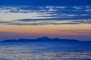 twilight scene of a small island with windy sea wave and cloudy sky with colorful sunset