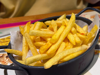 Crispy French fries served in a basket. Fast food, comfort snack, golden crispy texture.