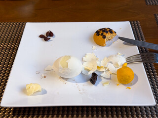 Leftover breakfast food on white plate after meal. Food waste, unfinished eating, casual dining...