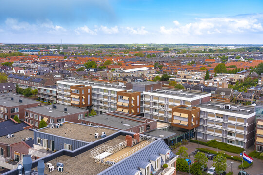Aerial view of neat rows of buildings with terracotta roofs juxtapose against the blue sky, and the Dutch flag flutters gently, Noordwijk, South Holland, Netherlands.