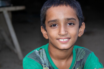 Smiling Young Boy Looking at Camera in Natural Light with a Simple Rural Background