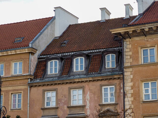 Naklejka premium Tiled roofs and attic windows of old colorful european houses against grey sky