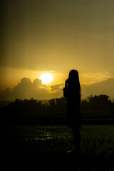 Fototapeta premium Silhouette of an Asian woman at sunset. Illustration of a lonely woman, an introverted woman. World Introvert Day.