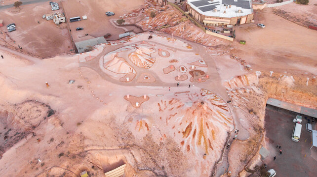 Aerial view of the landscape where the earth is painted in hues of peach and cream, dotted with structures and pathways, Coober Pedy, South Australia, Australia.