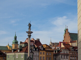 Fototapeta premium Panoramic view of the colorful roofs and architecture of Warsaw Old Town, with Sigismund's Column dominating the foreground.