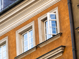 Obraz premium Close-up of the facade of an orange and yellow historic tenement house with white window frames.