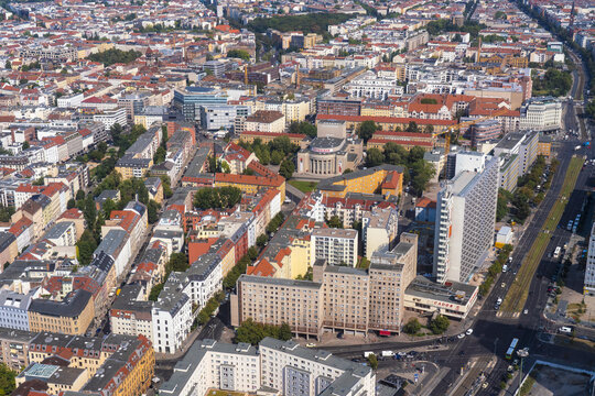 Aerial view of terracotta rooftops contrasting with modern structures and green spaces in the vibrant urban tapestry of Berlin Mitte, Berlin, Germany.