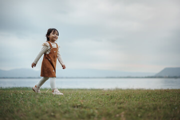 happy toddle girl walking on grass field near the river