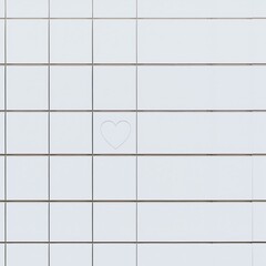 Simple white tiled building facade featuring a single etched outline of a heart symbolizing love and connection in urban design