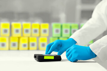 Scientist in blue gloves using a digital device in laboratory with colorful chemical containers on the background