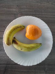 Top view of Two bananas and an orange on white plate, Healthy breakfast food