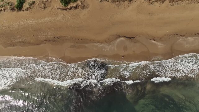 Aerial view of the sandy beach meeting the turquoise waters, creating a stunning contrast of textures and colors, Korission, Corfu, Greece.
