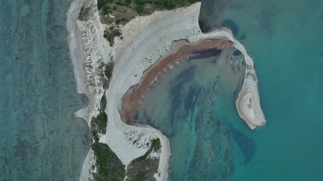 Aerial view of the stark white cliffs contrasting with the turquoise waters along the coastline of Agios Stefanos, Corfu, Greece.