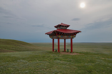 Gazebo in traditional folk style in the Kalmyk steppe on a cloudy evening in June. Republic of Kalmykia, Russian Federation