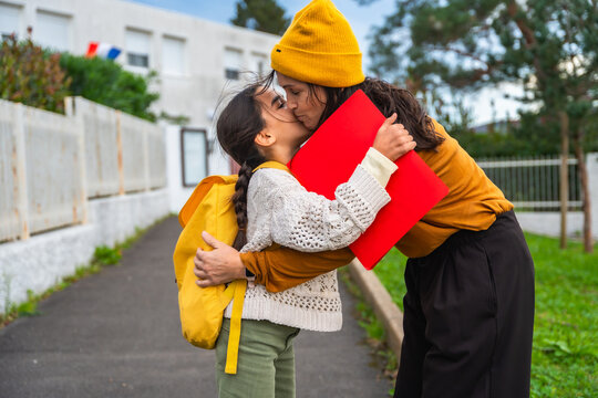 Mother kissing daughter goodbye before school