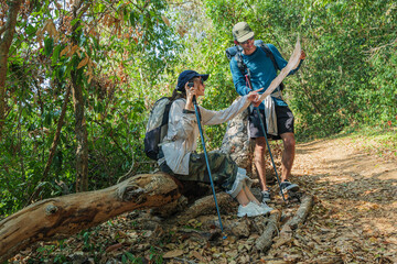 Young couple enjoy invigorating hike, exploring lush forest nature trail, consulting map for mountain walk direction, carrying backpacks and poles for challenging travel adventure