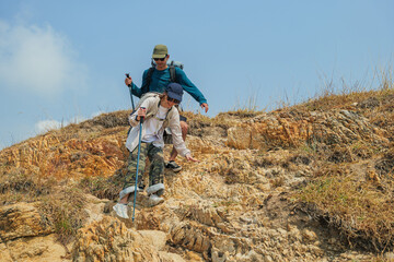 Naklejka premium Hiker couple enjoying nature walk up rugged mountain terrain, young people travel for outdoor adventure, active lifestyle, summer leisure activity