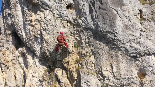  Flying near a mountain rescuer rappelling on a rocky wall with a drone