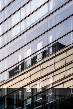 Modern architecture facade with reflective glass building creating urban abstract pattern detail and contemporary city design background composition