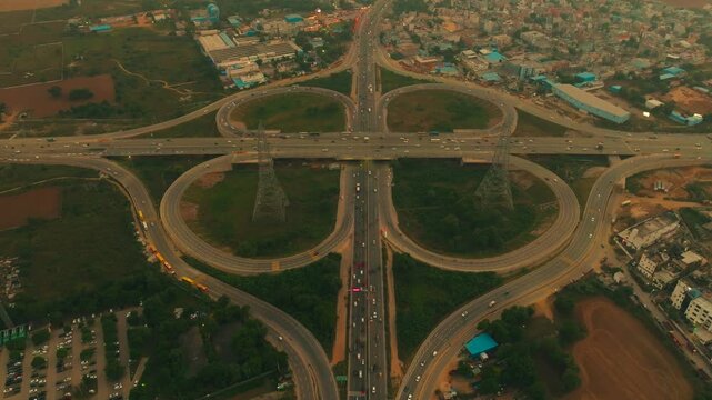Aerial view of the Gurugram Delhi Expressway showcasing the intricate cloverleaf interchange with vehicles moving along the roads, Gurugram, Haryana, India.