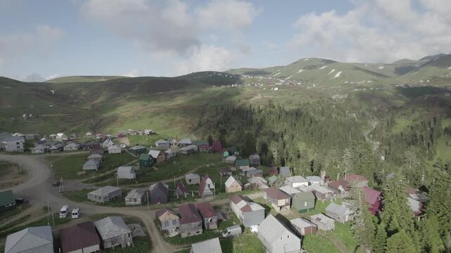 Aerial drone view of Gomis Mta, a mountain village in Georgia, featuring small wooden houses surrounded by patches of snow and green hills