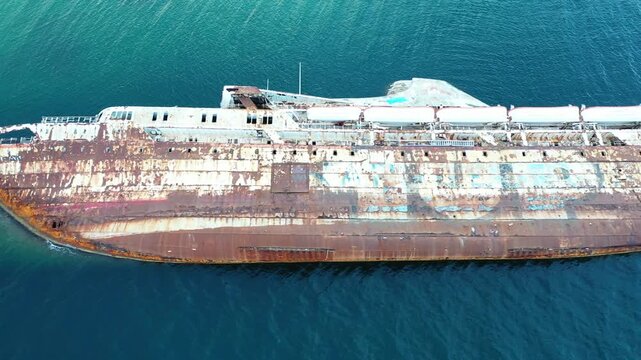 Aerial view of a decaying ship, its hull a canvas of rust and peeling paint, adrift in the tranquil blue sea waters, Athina, Kentrikos Tomeas Athinon, Greece.