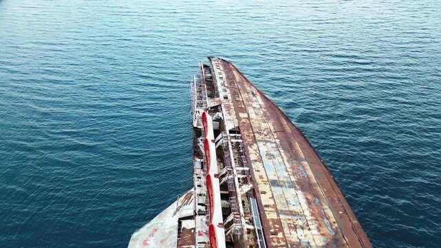 Aerial view of a rusty shipwreck contrasts against the serene blue sea, creating a stark visual narrative of decay meeting nature's resilience, Athina, Kentrikos Tomeas Athinon, Greece.