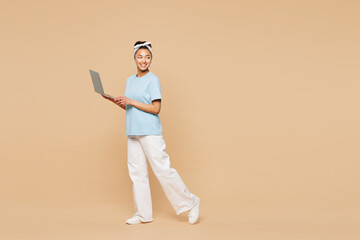 Full body young IT woman of African American ethnicity wearing blue t-shirt casual clothes hold use...