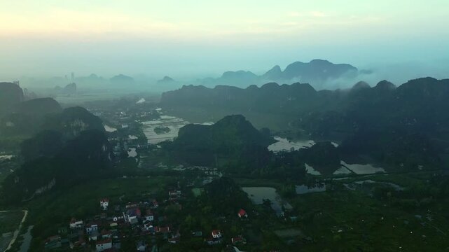 Aerial view of the dramatic karst landscape, where verdant mountains meet serene waters, creating a harmonious blend of nature's artistry, Hoa Lu, Ninh Binh, Vietnam.