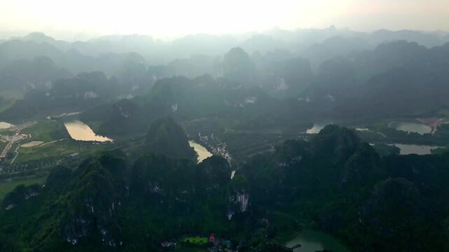 Aerial view of lush green limestone karsts jutting out of the tranquil waterways creating a stunning landscape, Hoa Lu, Ninh Binh, Vietnam.