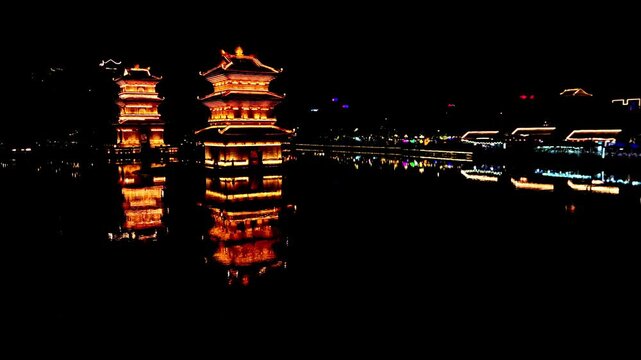 Aerial view of vibrant pagodas and buildings light up the night, reflecting in the still water, creating a stunning contrast against the darkness, Hoa Lu, Ninh Binh, Vietnam.