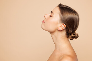 Side profile view beautiful half naked topless young woman 20s with nude make up close eyes isolated on beige brown color background studio portrait. Skin care healthcare cosmetic procedures concept.