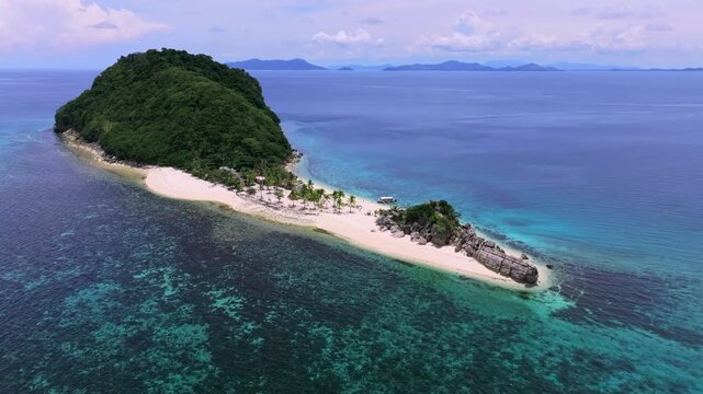 Aerial view of a lush green island surrounded by turquoise waters, contrasted by the white sand beach, Carles, Western Visayas, Philippines.
