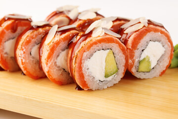 Delicious sushi rolls topped with almonds on a wooden board