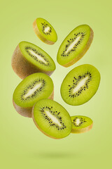 Slices kiwi fruit with rich green flesh, black seeds fly as flow on green background. Perfect for organic antioxidant food advertising, detox menu, fitness diet, product label, poster, design.