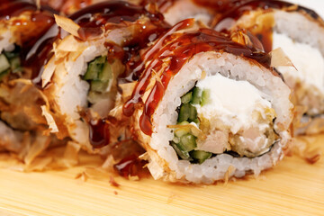 Delightful sushi rolls with rich sauce served on wooden board