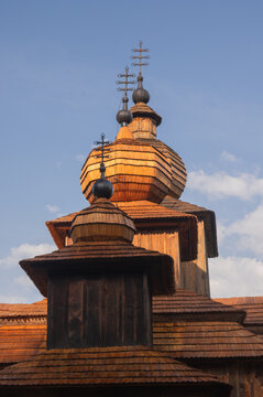 View of elaborate wooden architecture with dark, weathered textures and ornate crosses reaching towards a pale blue sky, Dobroslava, Presov Region, Slovakia.
