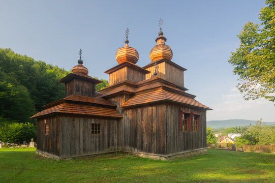 View of weathered wood textures and ornate onion domes distinguish the historic St. Parascheva Church nestled amid lush Slovakian greenery, Wooden Church of St. Parascheva, Presov Region, Slovakia.