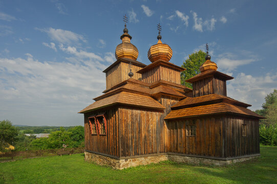 View of the weathered wooden church standing proudly with its three onion domes, a serene contrast against the vibrant green grass, Dobroslava, Presov Region, Slovakia.