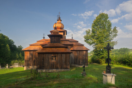 View of the rustic wooden church stands majestically on a grassy knoll, sunlight kissing its weathered facade, Dobroslava, Presov Region, Slovakia.