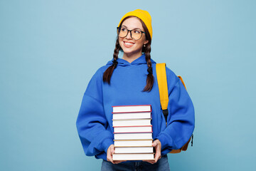 Young fun smiling cheerful happy smart woman reader student she wear casual clothes yellow backpack bag hold books isolated on pastel plain light blue color background. High college lifestyle concept.