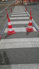 Pedestrian crossing with white and red colored bollards on asphalt
