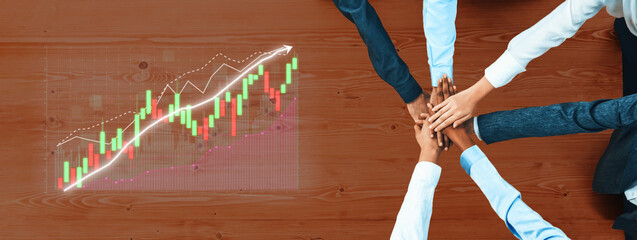 A group of diverse professionals collaborates on business growth strategies, placing hands together on a table while analyzing data trends displayed graphically. Axiom