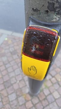 Signal Kommt yellow button for pedestrians at some traffic lights in Germany. Rainy day