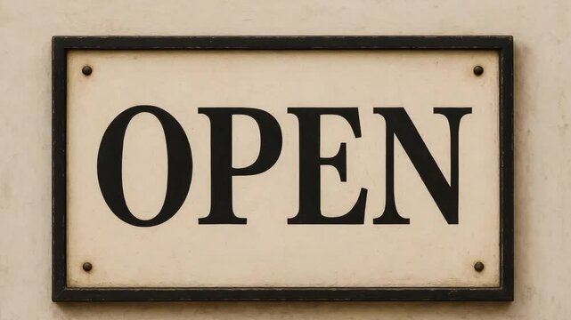 A framed OPEN sign mounted on a beige wall.