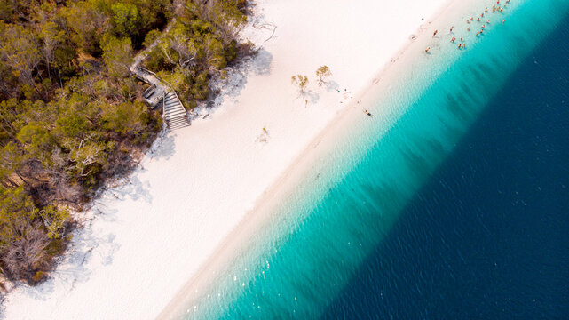Aerial view of the striking contrast between the pure white sands of Lake McKenzie and the deep azure waters, fringed by verdant forest, Lake McKenzie, Queensland, Australia.